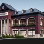 Red brick building with black roof, arches, and a clock tower with a sign that reads: Troy City Hall.