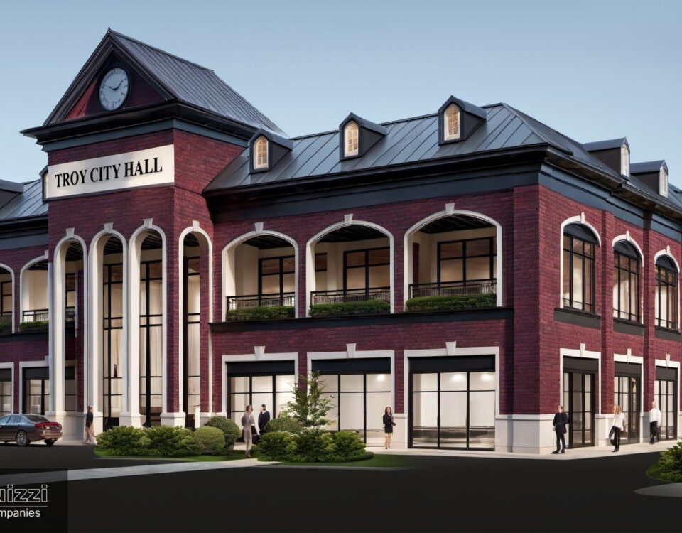 Red brick building with black roof, arches, and a clock tower with a sign that reads: Troy City Hall.